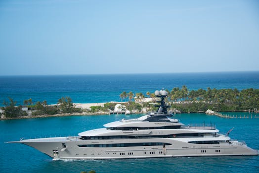 High-end yacht cruising along a tropical coastline with clear blue waters and lush greenery.